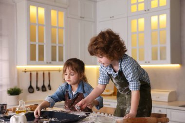 Yemek tarifi. Çocuklar mutfaktaki yemek tabağına çiğ kurabiye koyuyorlar.