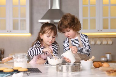 Yemek tarifi. Sevimli çocuklar mutfaktaki masada kurabiye için para kazanıyor.