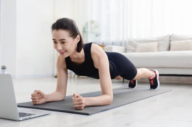 İnternetteki derste koçla tahta egzersizi yapan bir kadın. Spor ve sağlıklı yaşam tarzı