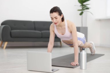 İnternetteki derste koçla tahta egzersizi yapan bir kadın. Spor ve sağlıklı yaşam tarzı