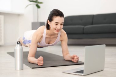 İnternetteki derste koçla tahta egzersizi yapan bir kadın. Spor ve sağlıklı yaşam tarzı