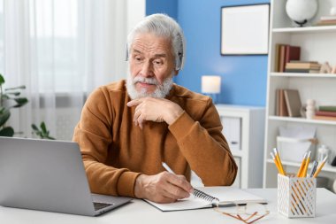 Üst düzey adam içeride masa başında öğrenirken not alıyor. Kendi kendine çalışma.