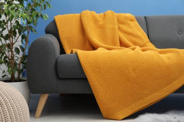 Oturma odasındaki kanepede turuncu yün battaniye.