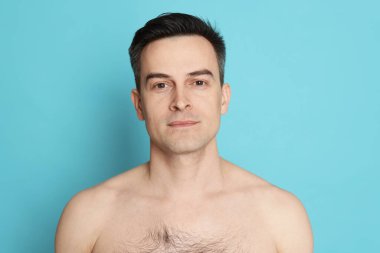 Açık mavi arka planda tıraş olduktan sonra yakışıklı bir adam.