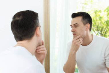 Evde aynanın yanında tıraş olduktan sonra yakışıklı bir adam.