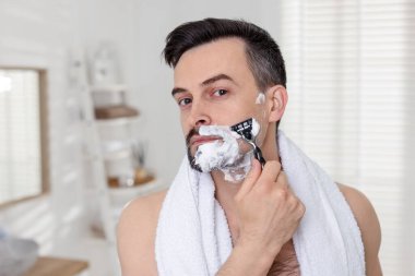 Yakışıklı adam evde tıraş olurken tıraş oluyor.