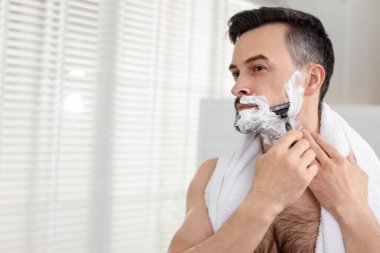 Evde jiletle tıraş olan yakışıklı bir adam. Metin için boşluk