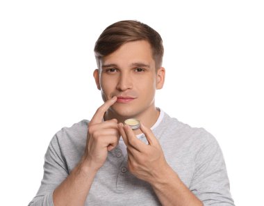 Dudak kremini beyaz arka planda dudaklarına süren genç bir adam.