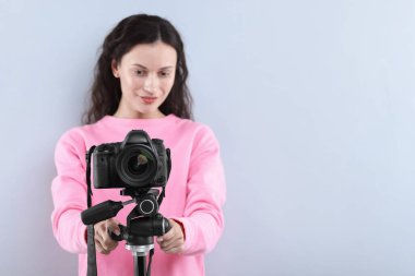 Açık gri arka planda profesyonel video kamerası olan kadın, seçici odaklı. Metin için boşluk