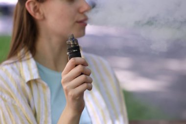 Dışarıda elektronik sigara içen genç bir kadın, yakın plan. Metin için boşluk