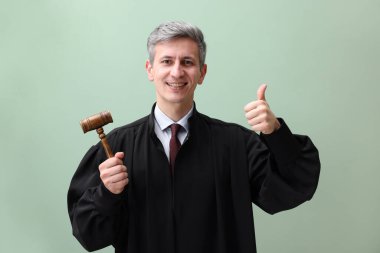 Çekiçle gülümseyen yargıç yeşil arka planda başparmak gösteriyor