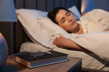 Evde uyuyan genç kadın, gözlük ve kitaba odaklan.