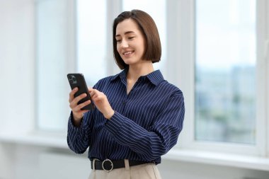 Ofiste akıllı telefonunu kullanan güzel bir kadın.