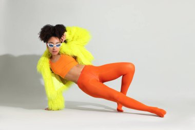 Beyaz arka planda şık giyinmiş güzel Brezilyalı bir kadının moda portresi.