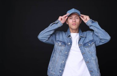 Siyah arka planda şık kot şapkalı genç adam, metin için yer var.