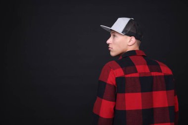 Siyah arka planda şık bir beyzbol şapkası giyen genç adam, mesaj için yer var.