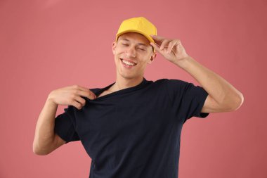 Pembe arka planda şık bir beyzbol şapkası takan genç adam.