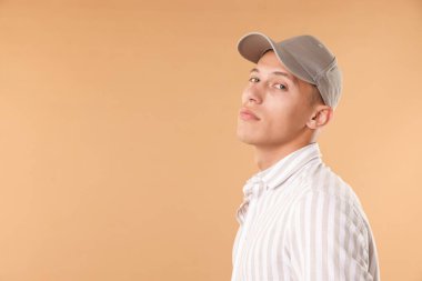 Beyzbol şapkalı genç adam bej arka planda, mesaj için yer var.