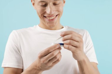 Açık mavi arkaplanda kontak lensleri alan adam, yakın plan