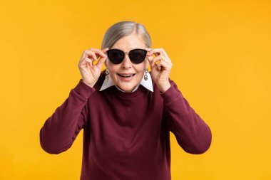 Turuncu arka planda şık giyinmiş mutlu bir son sınıf kadını.