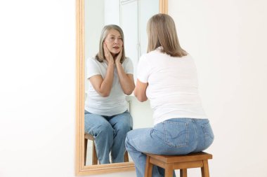 Güzel son sınıf öğrencisi kadın aynada kendine bakıyor.