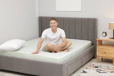 Evdeki yumuşak yatakta oturan adam