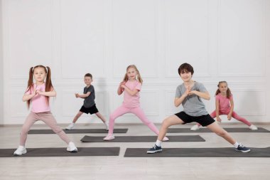 Sınıftaki minderler üzerinde yoga yapan bir grup çocuk.