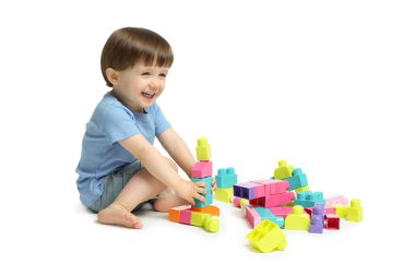 Beyaz arka planda tuğlalarla oynayan sevimli küçük çocuk.