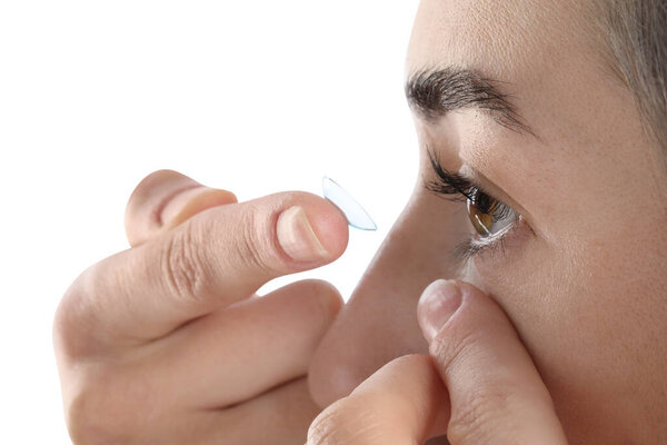 Woman putting in contact lens on white background, closeup