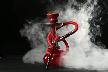 Siyah arka planda duman olan ahşap masada nargile.