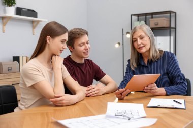 Tabletli emlakçı ofiste bir çiftle çalışıyor.