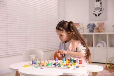 Motor beceri geliştirme. Küçük kız matematik oyunuyla oynuyor Beyaz masada sayıları avlıyor