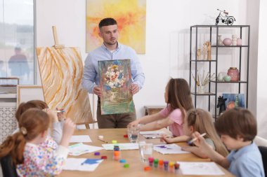 Çocuklara resim dersinde resim yapmayı öğreten bir adam.