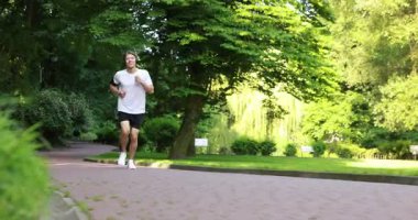 Parkta çalışan kulaklıklı bir sporcu.