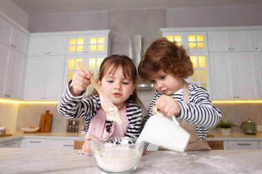 Yemek tarifi. Sevimli çocuklar mutfaktaki masada kurabiye için hamur yapıyorlar, düşük açılı.