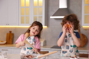 Küçük çocuklar mutfakta yemek yaparken eğleniyorlar.