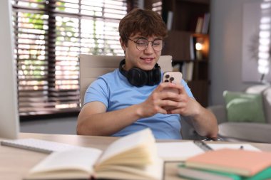 Evde ders çalışırken kulaklık takan genç bir öğrenci.