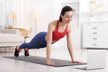 İnternetteki derste koçla tahta egzersizi yapan bir kadın. Spor ve sağlıklı yaşam tarzı