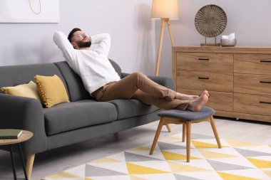 Evdeki kanepede dinlenen yakışıklı adam.