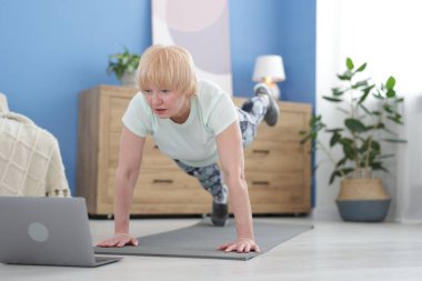 Spor giyim bölümünde son sınıf öğrencisi. Evde online ders sırasında kalas egzersizi yapıyor.