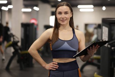 Spor salonunda panosu olan profesyonel kişisel antrenör.