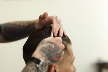 Profesyonel berber berber dükkanında şık saç kesimi yapıyor, yakın plan.