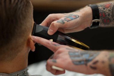 Berber dükkanında müşteriyle çalışan profesyonel berber, yakın plan.