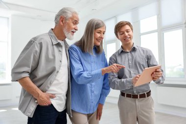 Tabletle gülümseyen emlakçı evde çiftlerle çalışıyor.