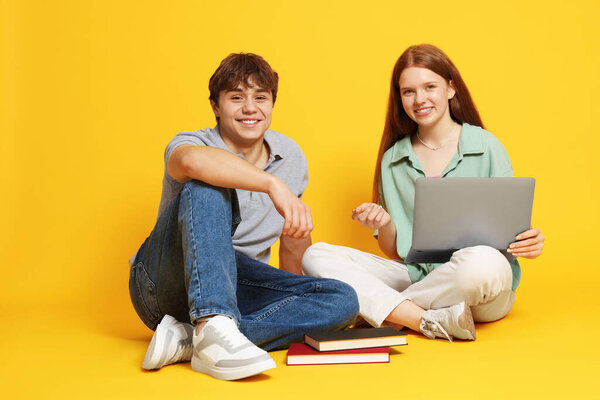 Подросток и мальчик с ноутбуком на желтом фоне