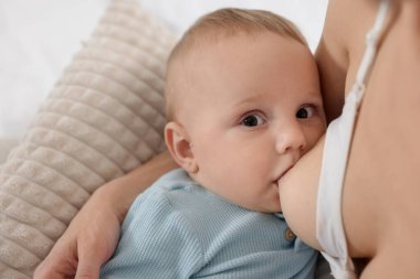 Anne küçük bebeğini evde emziriyor, yakın plan.