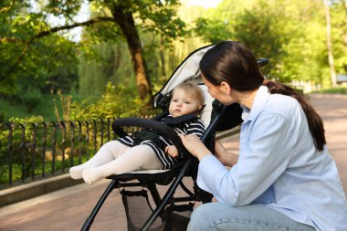 Parkta bebek arabasında sevimli bebeğiyle annesi