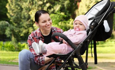 Parkta bebek arabasında sevimli bebeğiyle annesi