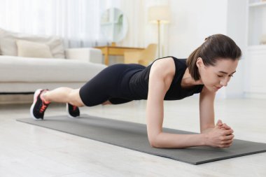 Evde tahta egzersizi yapan bir kadın. Spor ve sağlıklı yaşam tarzı