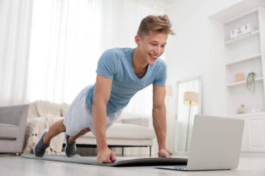 Evdeki koçla çevrimiçi derste tahta egzersizi yapan adam. Spor ve sağlıklı yaşam tarzı